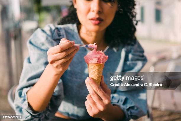 young woman eating ice cream cone - sorbetto foto e immagini stock