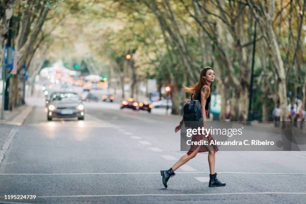 young woman crossing city street - crossed imagens e fotografias de stock