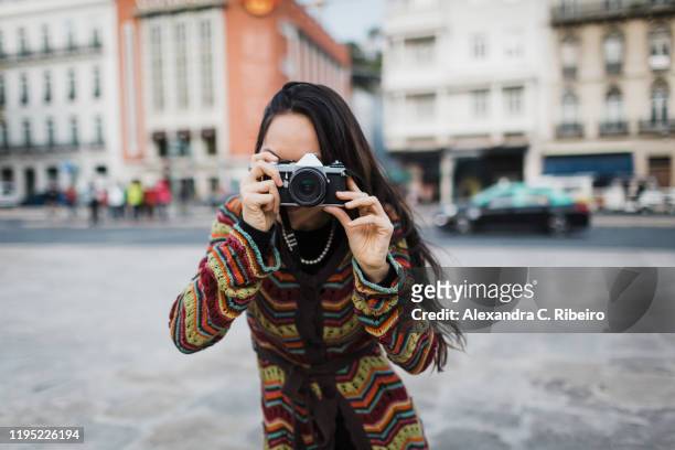 portrait female tourist using camera on city street - pointing at camera - fotografias e filmes do acervo