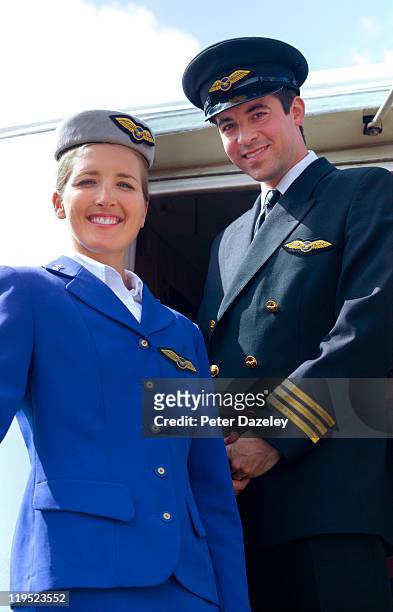 air hostess and pilot on steps of airplane - fliegermütze stock-fotos und bilder