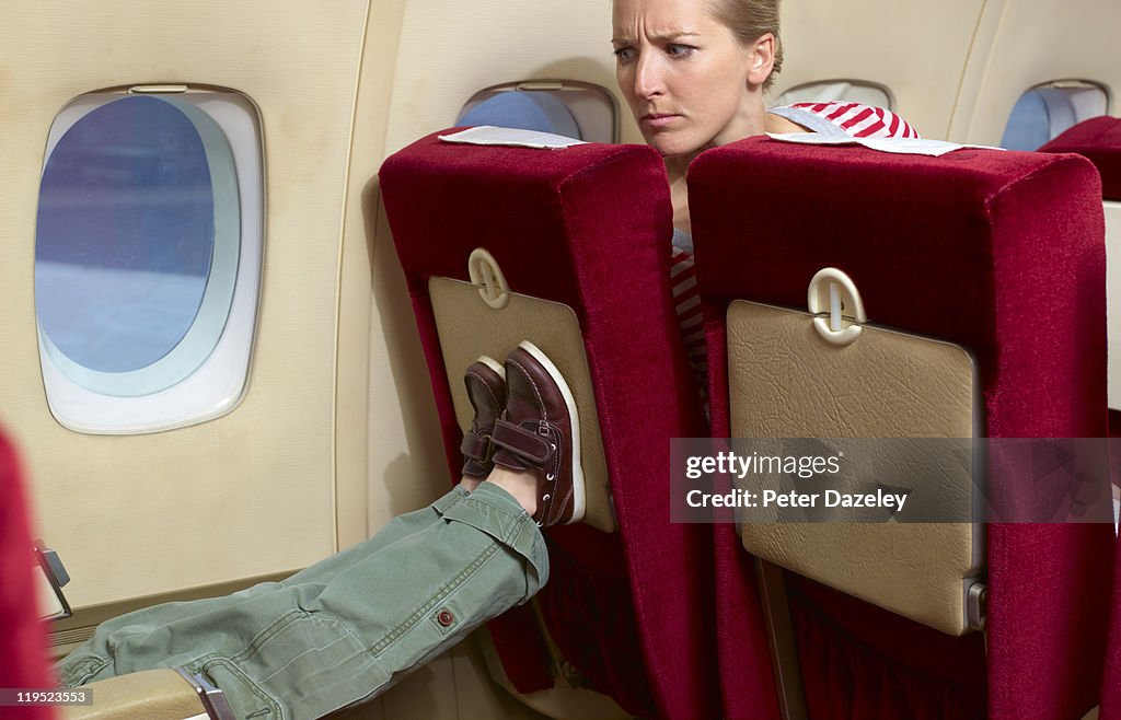 Boy kicking woman's seat on plane