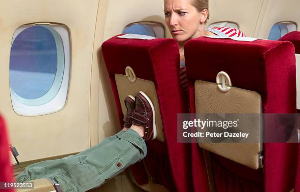 boy kicking woman's seat on plane - provocation bildbanksfoton och bilder