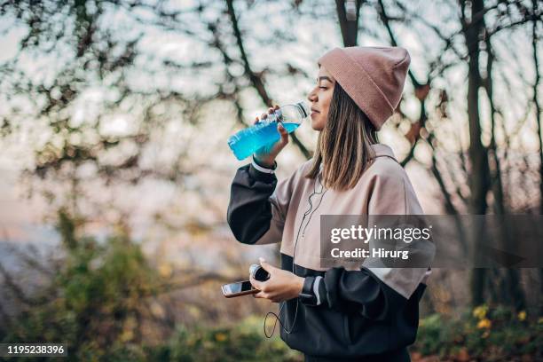 junge sportlerin trinkt energydrink in der natur - energydrink stock-fotos und bilder