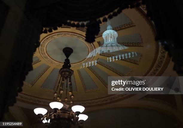 The dome of the US Capitol is seen reflected in a window of the Ohio Clock corridor outside the Chamber where Senators debate during the impeachment...