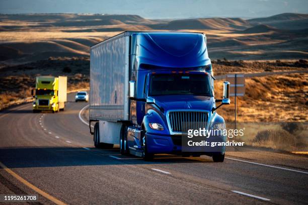 long haul semi-truck rolling down a four-lane highway at dusk - semi truck stock pictures, royalty-free photos & images