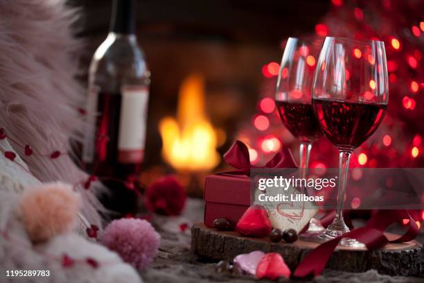 valentine's day red wine and a gift with chocolates in front of the fireplace - valentines day dinner stock pictures, royalty-free photos & images