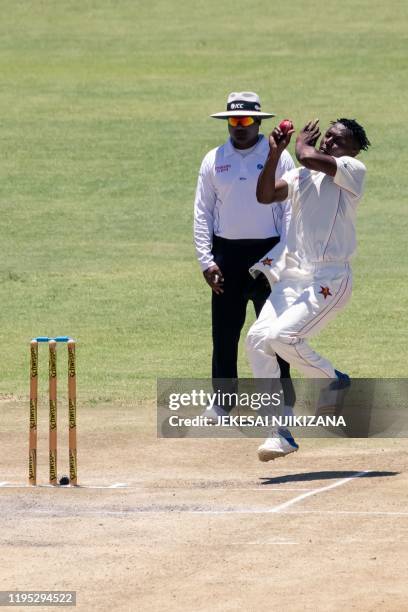 Zimbabwe's Victor Nyauchi delivers a ball as umpire Nitin Menon looks on during the fourth day of the first Test cricket match between Zimbabwe and...