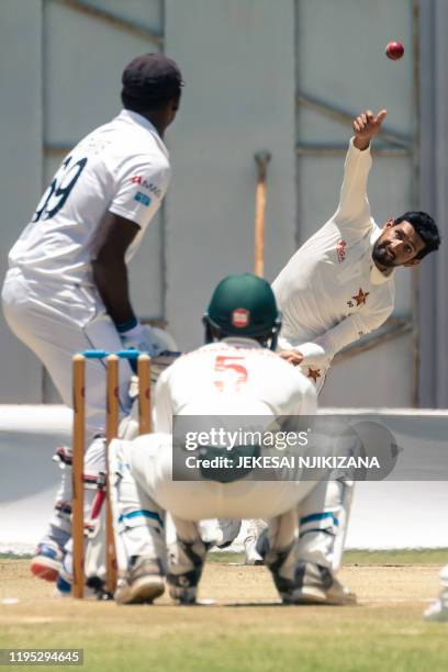 Zimbabwe's Sikandar Raza delivers a ball to Sri Lanka's Angelo Mathews as Zimbabwe's Regis Chakabva looks on during the fourth day of the first Test...