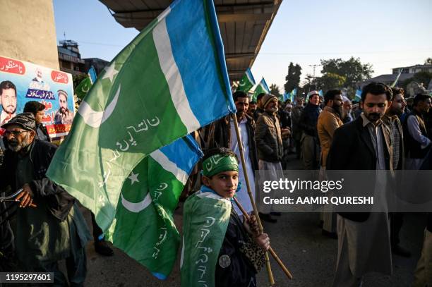 Supporter of Pakistani Islamic political party Jamaat-e-Islami waves party flags as he gathers with others during a protest against the price hike...