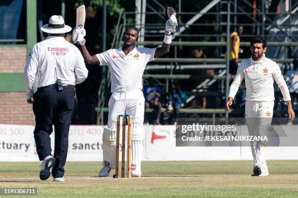 Sri Lanka's batsman Angelo Mathews celebrates reaching 200 runs as umpire Marais Erasmus and Sikandar Raza Butt look on during the fourth day of the...