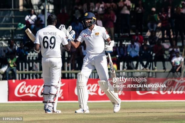 Sri Lanka's batsman Angelo Mathews is congratulated by teammate Kasun Rajitha after reaching 200 runs during the fourth day of the first Test cricket...