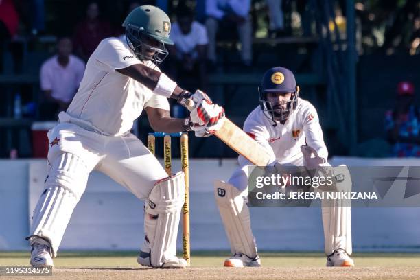 Zimbabwe's batsman Prince Masvaure hits the ball past wicket keeper Niroshan Dickwella during the fourth day of the first Test cricket match played...