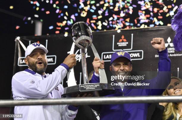 Coaches Jimmy Lake and Chris Petersen of the Washington Huskies celebrate with the game trophy after defeating the Boise State Broncos 38-7 in the...