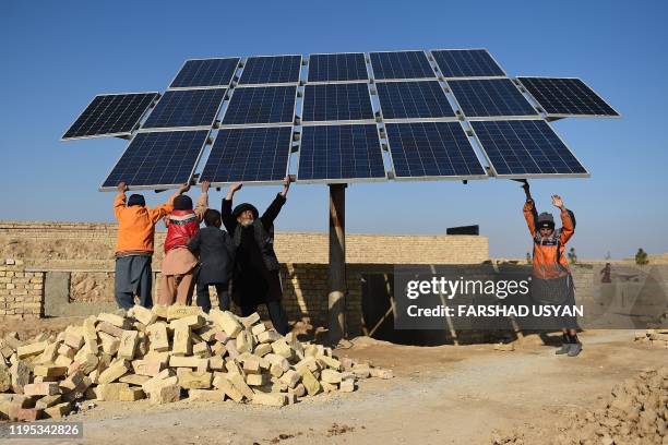In this photograph taken on November 28 internally displaced people turn a solar panel towards the sun as they use solar power to collect water in an...