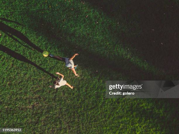 drone view on man playing soccer with teengage girl - aerial football stock pictures, royalty-free photos & images