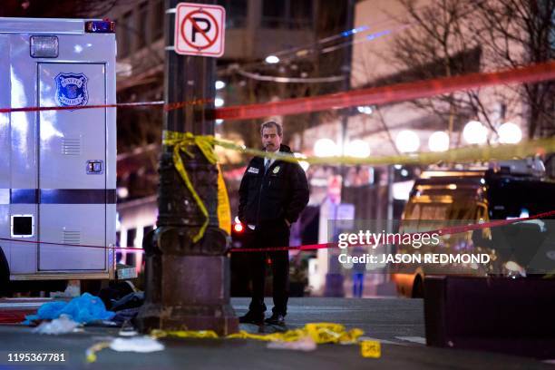 Graphic content / A homicide detective is pictured at the scene of a shooting that left one person dead and seven injured, including a child, in...