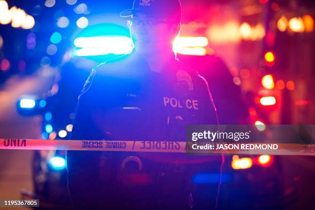 Graphic content / A Seattle Police officer is pictured at the scene of a shooting that left one person dead and seven injured, including a child, in...