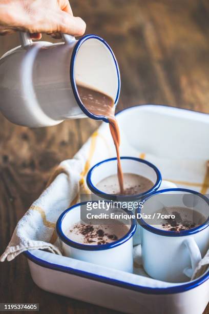 pouring creamy hot chocolate into rustic enamel coffee cups - hot chocolate foto e immagini stock