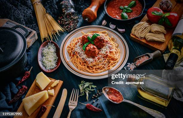 espaguetis con albóndigas e ingredientes en ollas rústicas. disparo tomado en mesa azulada de madera en la cocina rústica - meatball fotografías e imágenes de stock