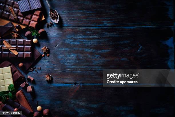 low-key-bild einer vielzahl von schokolade und bombonen mit getrockneten früchten. altmodischer stil auf einem blauen rustikalen tisch mit kopierraum - food photography dark background blue stock-fotos und bilder
