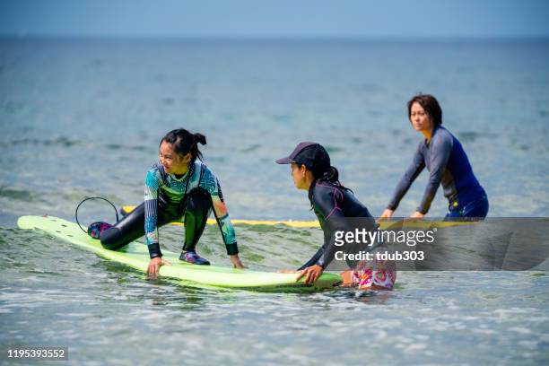 teenage girl taking a surfing lesson from her mother - japan 12 years girl stock pictures, royalty-free photos & images