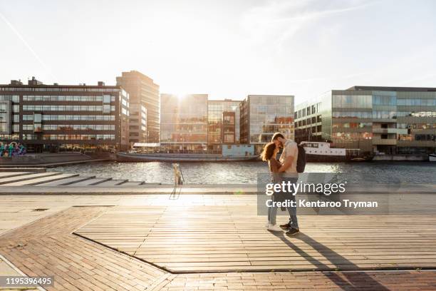 couple embracing while standing on promenade in city during summer - malmo sweden stock pictures, royalty-free photos & images