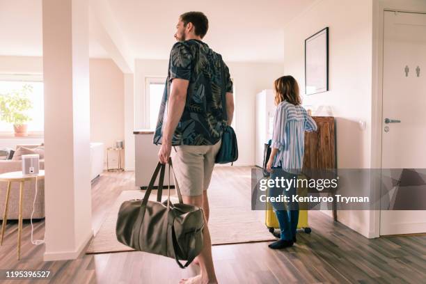 couple walking with luggage in apartment during staycation - llegada fotografías e imágenes de stock