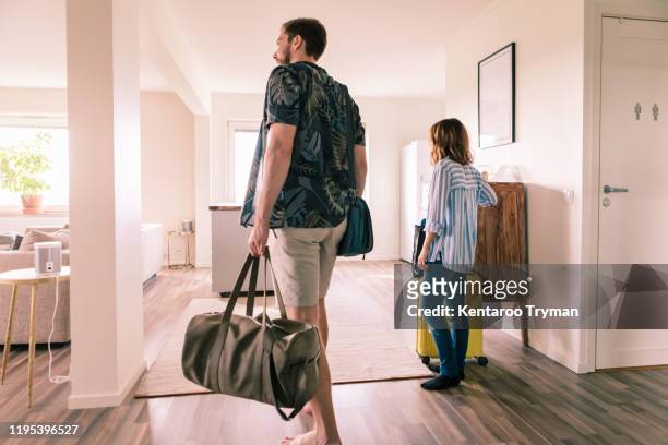 couple walking with luggage in apartment during staycation - chegada imagens e fotografias de stock