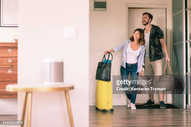 full length of couple with luggage looking around in apartment while standing at doorway - woman entering home stock-fotos und bilder