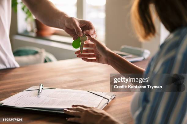 cropped image of owner giving house keys to tenant after filling rental forms - landlord stock pictures, royalty-free photos & images