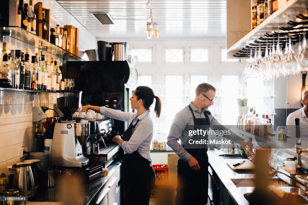 Male and female coworkers working in kitchen at restaurant