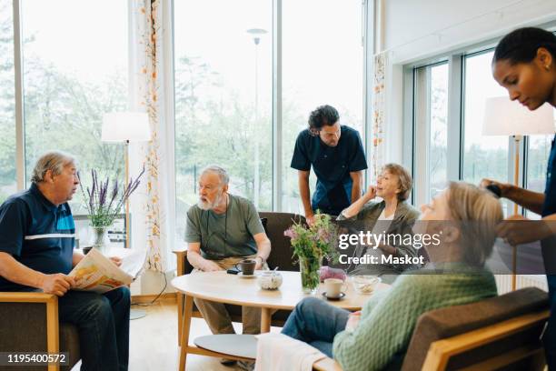 male and female nurses taking care of elderly retired people at nursing home - retirement community stock pictures, royalty-free photos & images