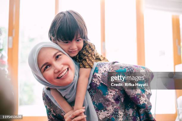 beautiful mother piggyback her son - batik indonesia stock pictures, royalty-free photos & images