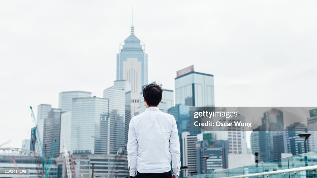 Rear view of professional man standing against the cityscape of the financial commercical buildings