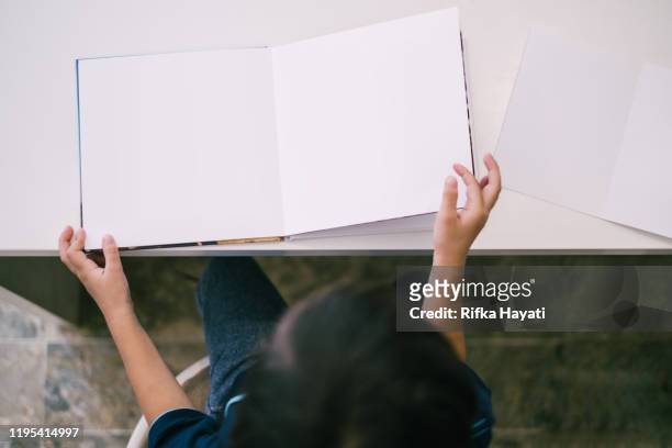 top view - happy asian little boy reading book - book hand stock pictures, royalty-free photos & images