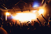 cheering crowd of unrecognized people at a rock music concert. concert crowd in front of bright stage lights and smoke. Concert audience at music concert.