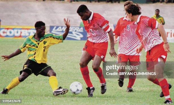 Jamaica's Steve Malcolm tries to dribble past Canada's Rany Samuel, Collin Miller and Ian Fraser 07 September in their World Cup qualifying match in...