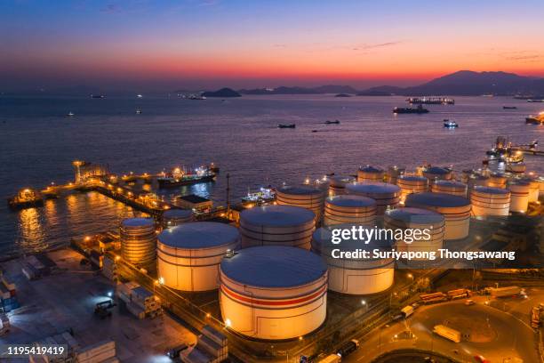 aerial view oil tanker warehouse with loading dock at dusk for transportation oil from refinery on the sea. - gas storage stockfoto's en -beelden