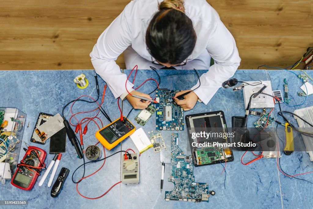 Female electronic engineer testing computer motherboard in laboratory