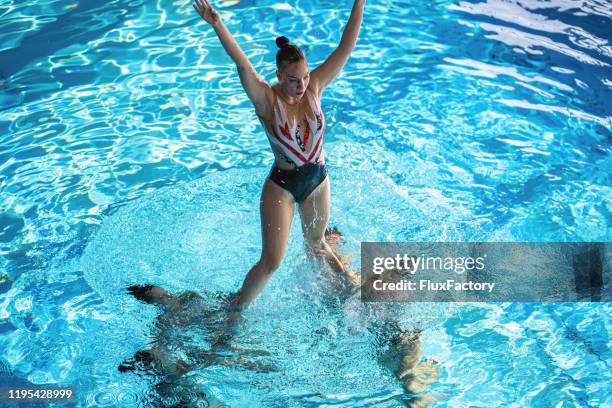 groupe de natation synchronisé restant dans une piscine pendant une exécution - synchronized swimming photos et images de collection