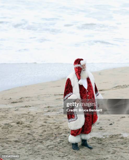 Person dressed like Santa Claus walks along the coast line on December 14, 2019 in Manhattan Beach, California.