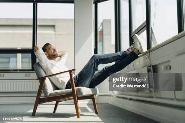 mature businessman relaxing at the window in empty office - sitting chair office relax stock pictures, royalty-free photos & images