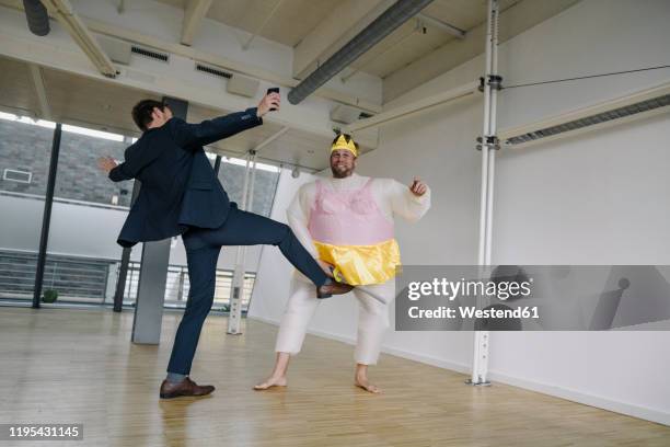 businessman kicking man dressed up as a ballerina in office - groyne stock pictures, royalty-free photos & images