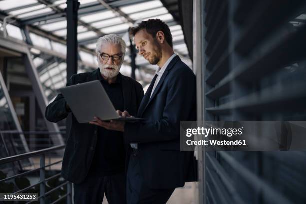 two businessmen using laptop in office together - business consulting stock-fotos und bilder