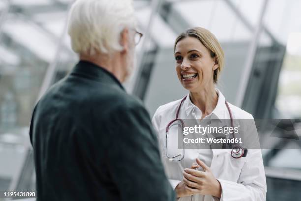 smiling female doctor talking to senior man - male looking content stock pictures, royalty-free photos & images