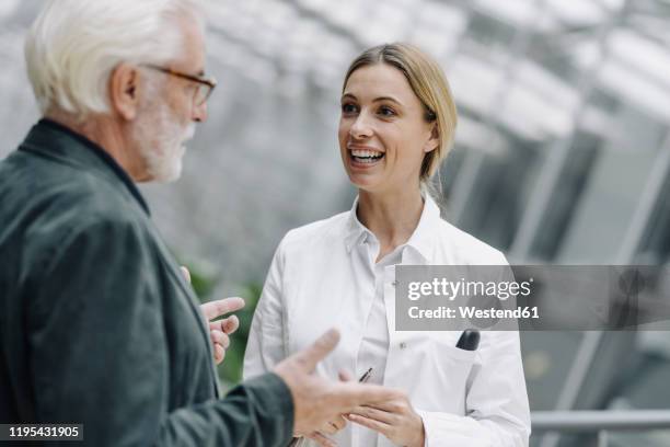 smiling female doctor talking to senior man - old man young woman stockfoto's en -beelden