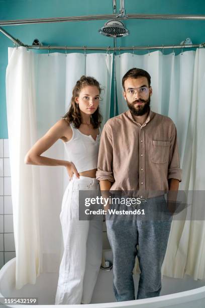 young couple standing in bath tub - shower man woman washing stock pictures, royalty-free photos & images