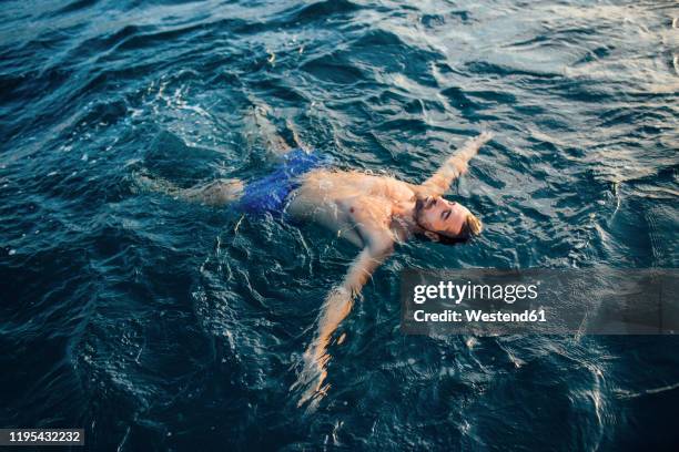 young man floating on water - drijven stockfoto's en -beelden