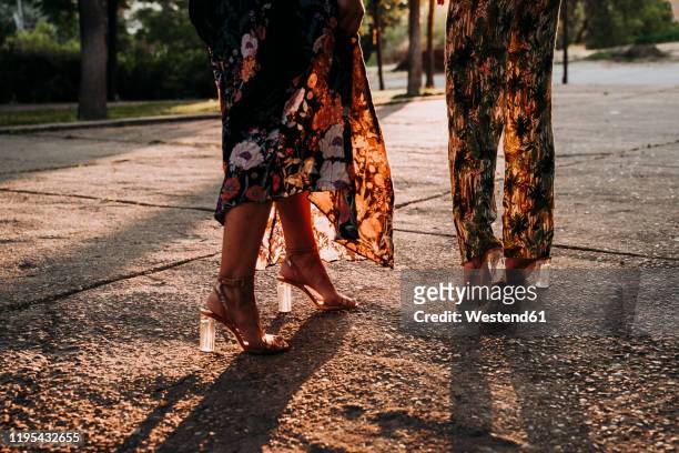 feet of two elegant women walking outdoors at sunset - tacones altos fotografías e imágenes de stock