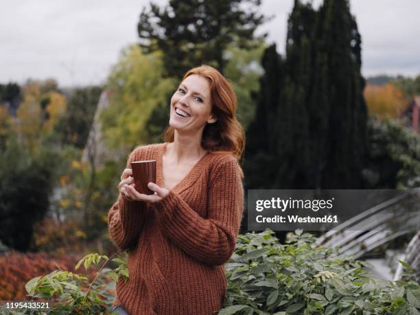 woman standing on balcony, drinking coffee - portrait älter trinken stock-fotos und bilder